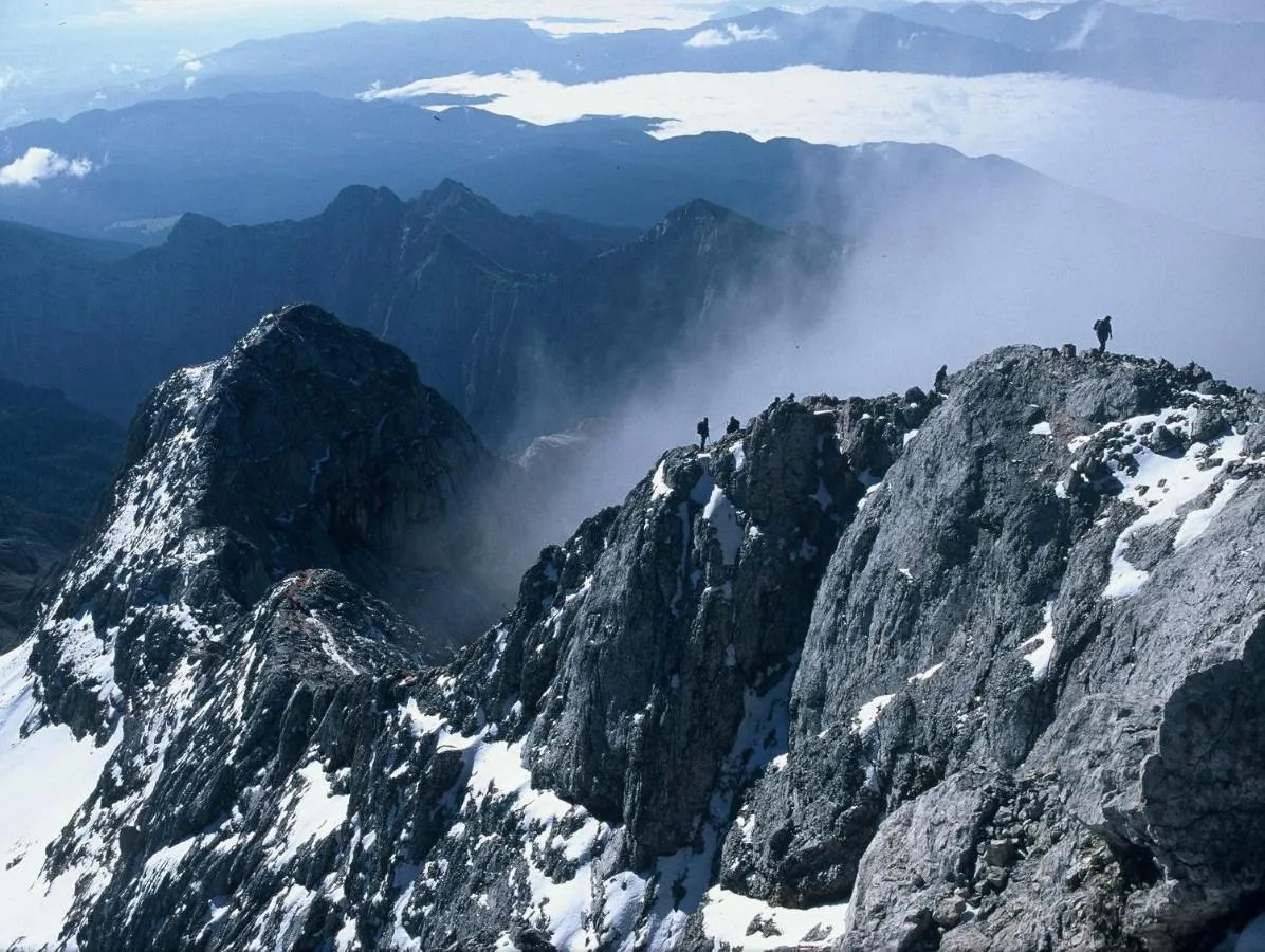 Pohodnika na skalnem vrhu nad oblaki
