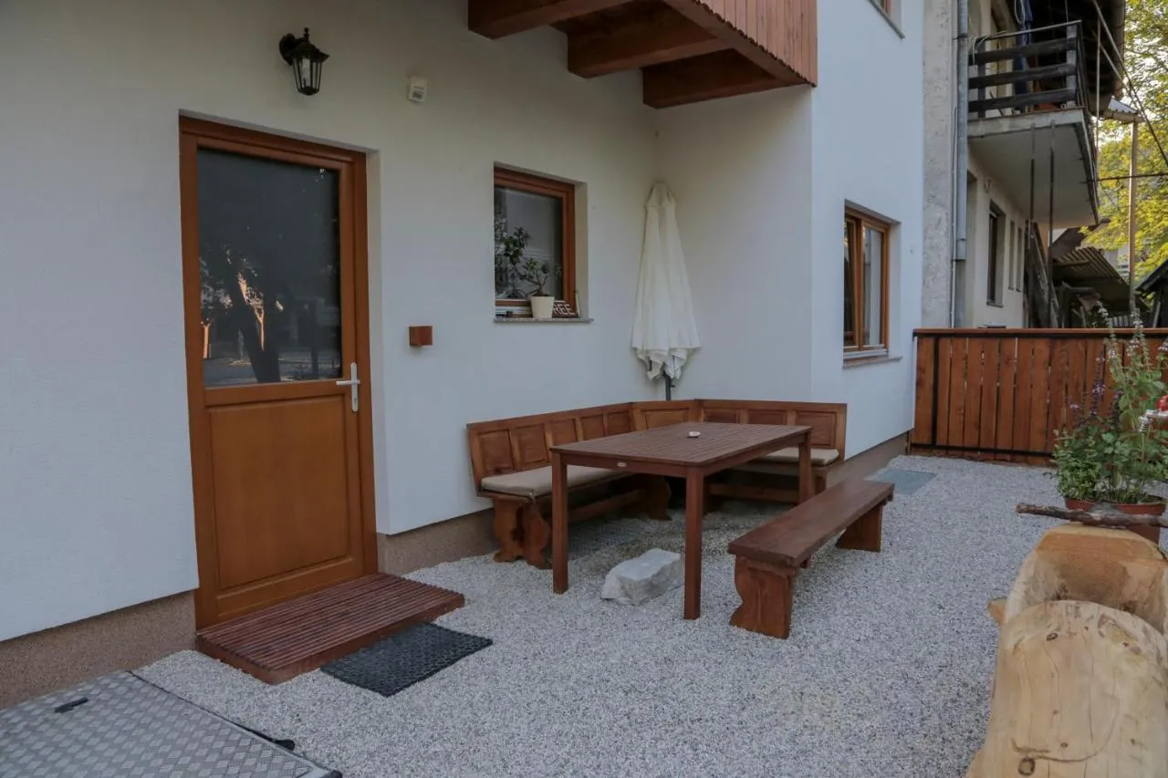 Terasa z leseno mizo in klopmi pred vhodom v apartma
